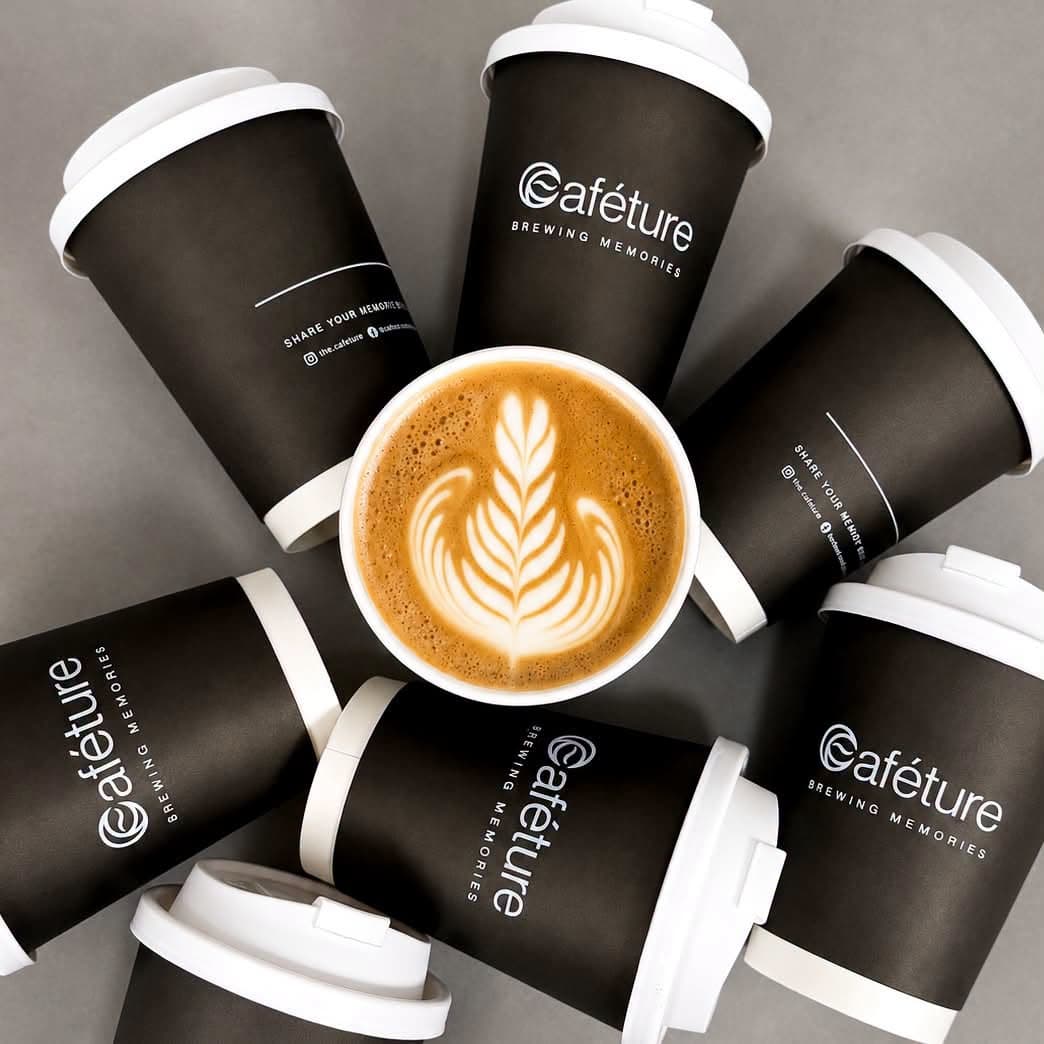 A latte with rosetta art among Caféture cups